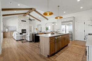 View from the kitchen overlooking living area with gas fireplace and exposed wooden beams