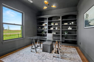 Office with built-in shelving, custom light fixture, and over-sized window