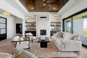 Living area with stone gas fireplace surrounded by built-in shelving looking into the office