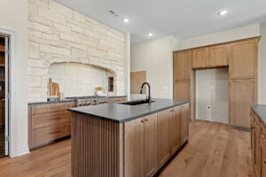 Kitchen with gas range built-in to stone wall, built-in cabinetry for refrigerator